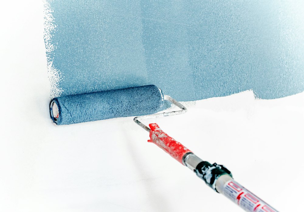 Paint roller applying fresh blue paint